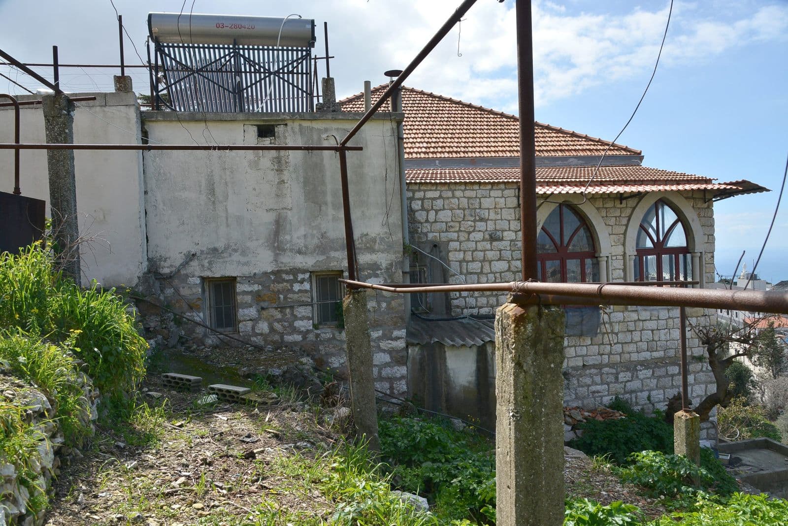 An annex of the house with worn walls and a solar water heater on the roof.