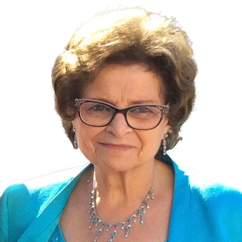 Portrait de Nehmat Bassal, souriante, avec des lunettes et un collier.